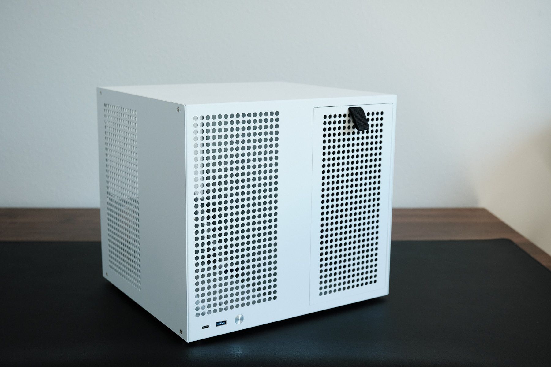 The white Sagittarius 8-bay NAS case viewed from the front left, showing the perforated front and side panels with a magnetic pull tab