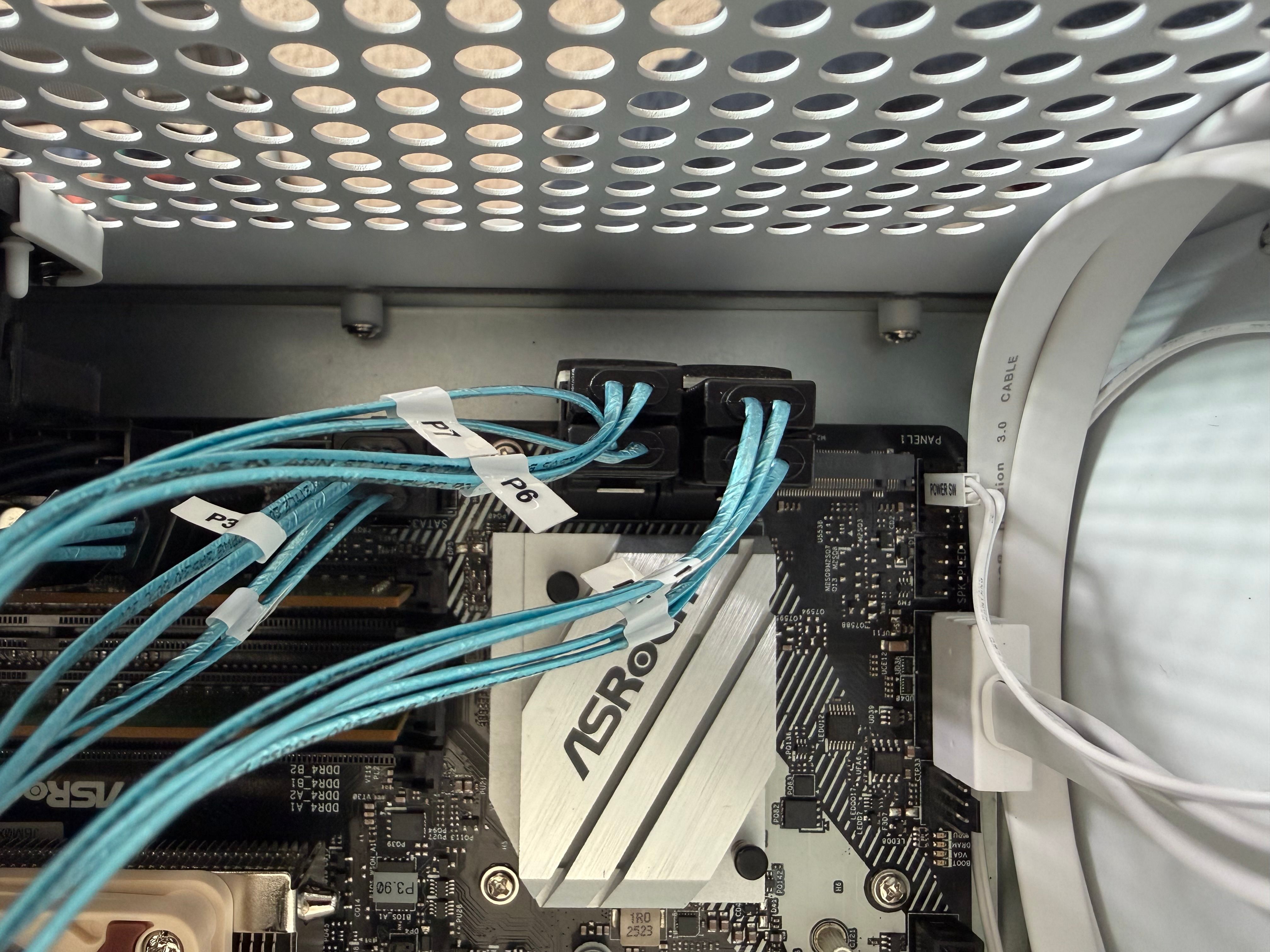 Close-up of four right-angle SATA adapters connected along the edge of the motherboard, with labeled blue SATA cables running across it.