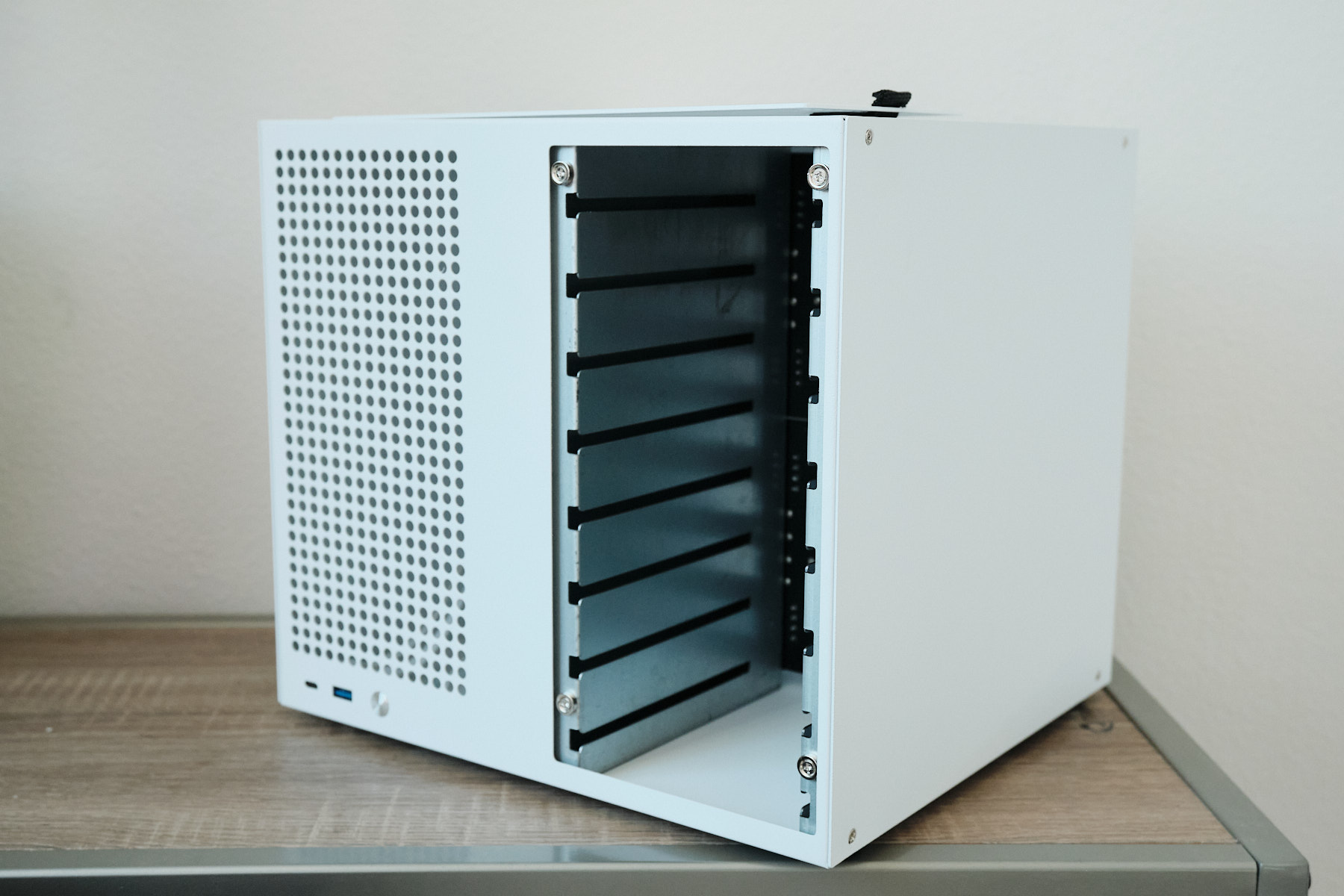 Front-right angle of the Sagittarius NAS case with the side panel removed, showing the eight 3.5-inch drive bay slots